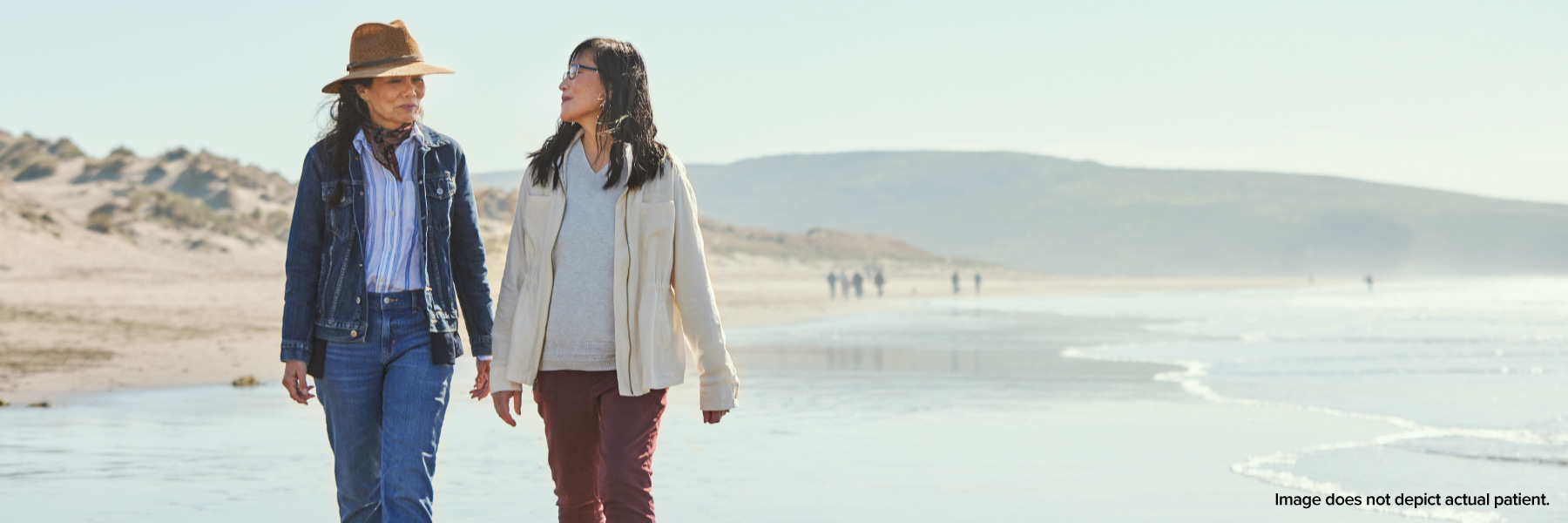 Two women talking and walking on the beach by the water